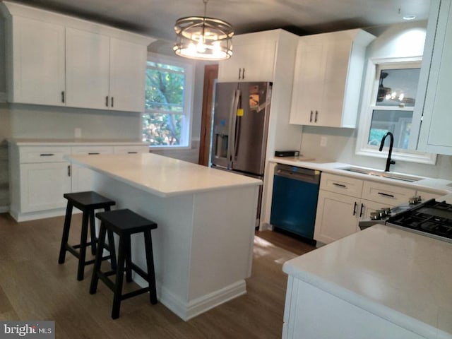 kitchen with stainless steel appliances, pendant lighting, a kitchen island, and white cabinets