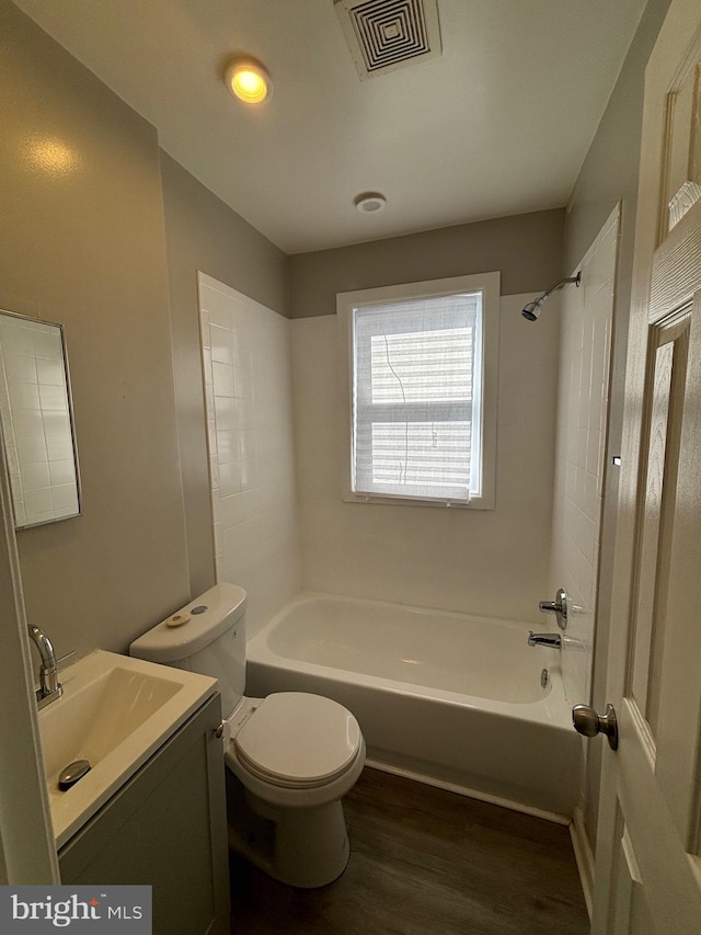 full bathroom with toilet, tiled shower / bath combo, vanity, and wood-type flooring