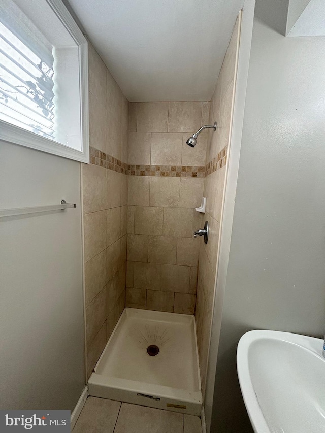 bathroom with a tile shower, sink, and tile patterned flooring