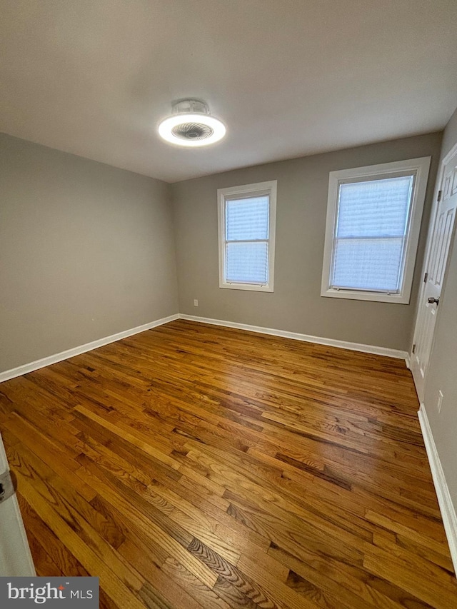 empty room with hardwood / wood-style floors and a healthy amount of sunlight