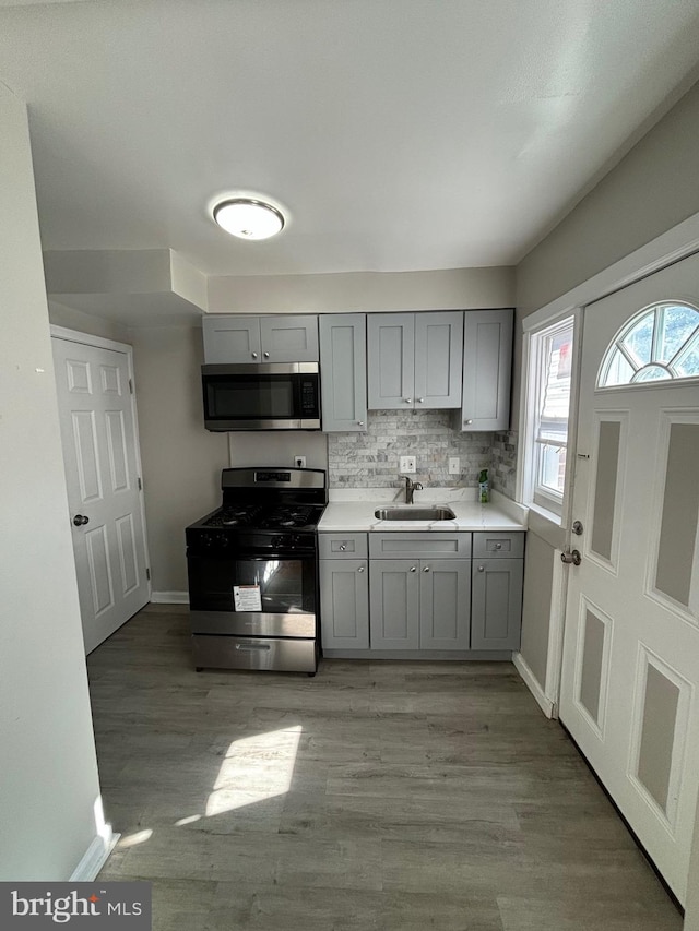 kitchen with gray cabinetry, light hardwood / wood-style floors, stainless steel appliances, and sink