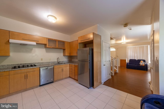 kitchen featuring light stone counters, extractor fan, light hardwood / wood-style flooring, sink, and stainless steel appliances