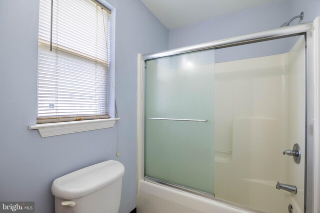 bathroom with toilet and shower / bath combination with glass door