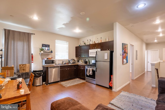 kitchen featuring tasteful backsplash, sink, light hardwood / wood-style floors, stainless steel appliances, and dark brown cabinetry