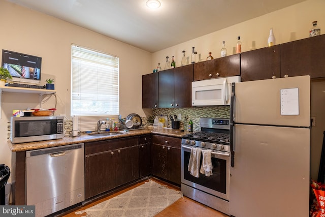 kitchen featuring dark brown cabinets, backsplash, sink, light hardwood / wood-style floors, and stainless steel appliances