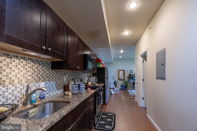 kitchen featuring electric panel, light stone counters, appliances with stainless steel finishes, light hardwood / wood-style flooring, and sink