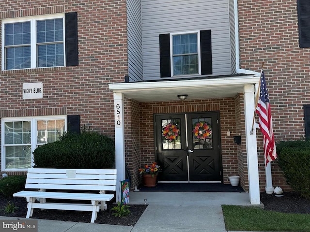 property entrance featuring french doors and brick siding