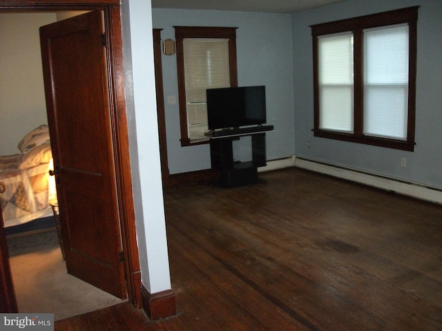 living room featuring a baseboard heating unit and dark wood-type flooring