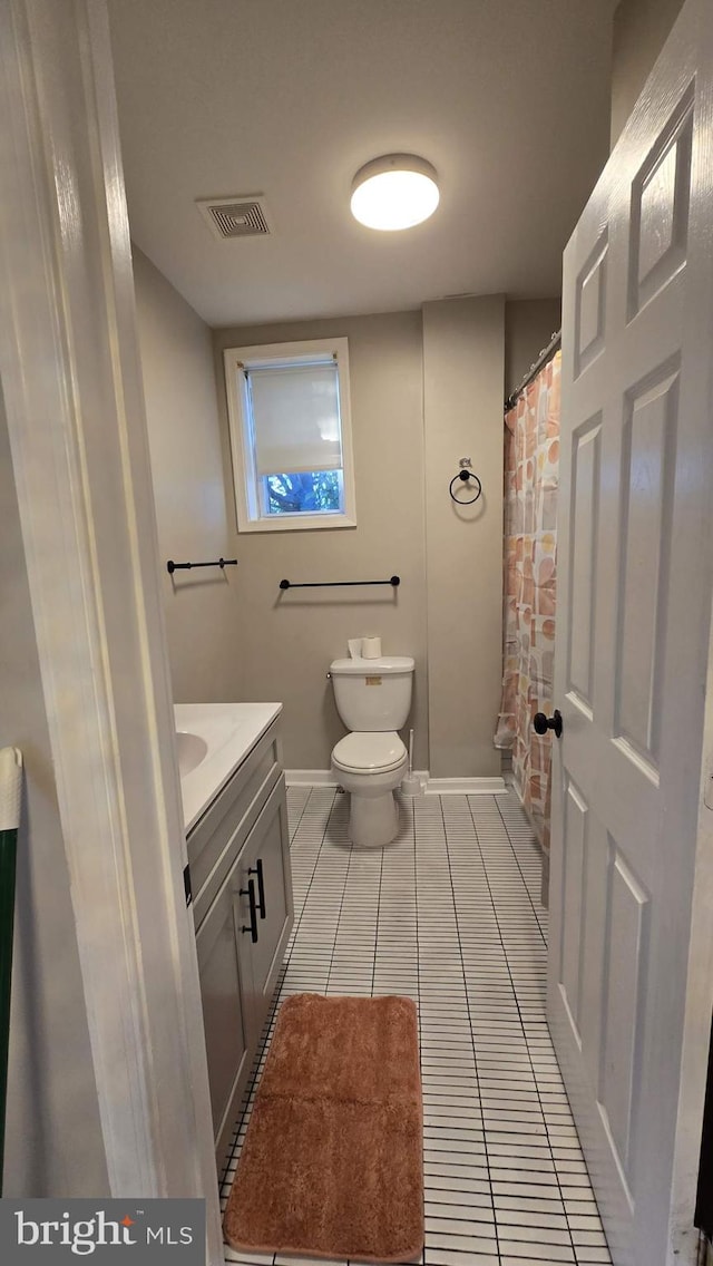 bathroom featuring toilet, a shower with curtain, vanity, and tile patterned floors