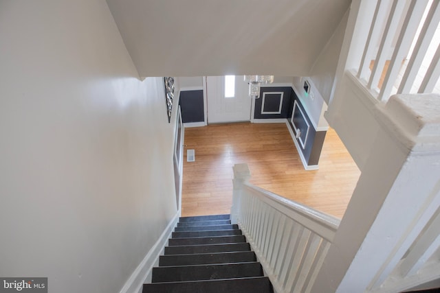 stairs featuring an inviting chandelier and hardwood / wood-style flooring