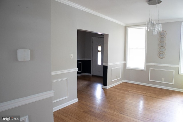 unfurnished dining area with ornamental molding, hardwood / wood-style flooring, and an inviting chandelier