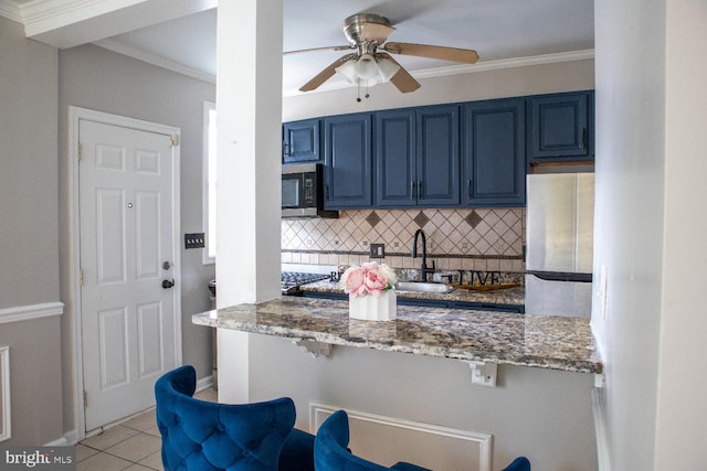 kitchen with blue cabinetry, sink, white refrigerator, and light stone counters