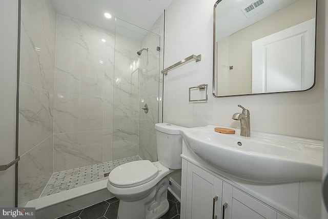 bathroom featuring vanity, tiled shower, toilet, and tile patterned flooring