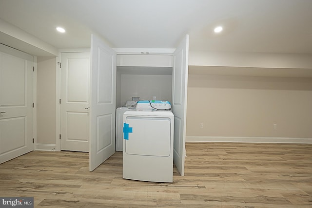 clothes washing area featuring light hardwood / wood-style floors and washer / clothes dryer