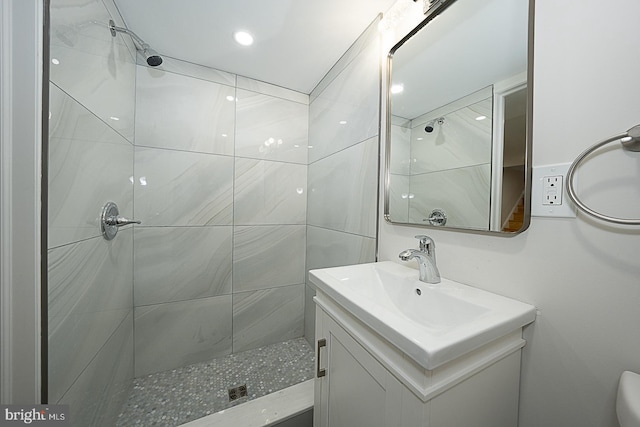 bathroom with vanity, tiled shower, and toilet