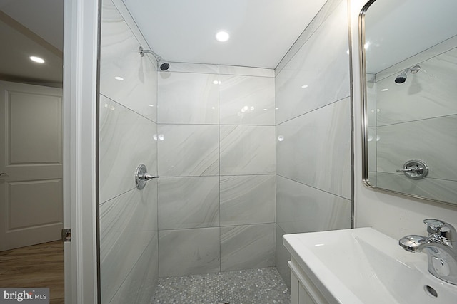 bathroom with a tile shower, vanity, and hardwood / wood-style floors