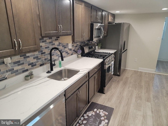 kitchen featuring dark brown cabinets, light stone counters, light hardwood / wood-style flooring, sink, and stainless steel appliances