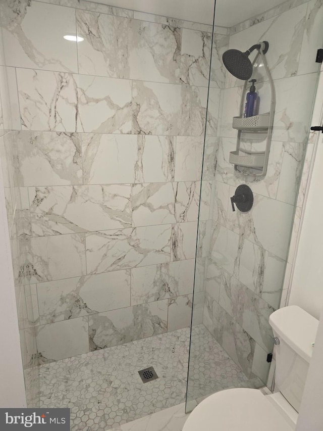 bathroom featuring toilet and a tile shower