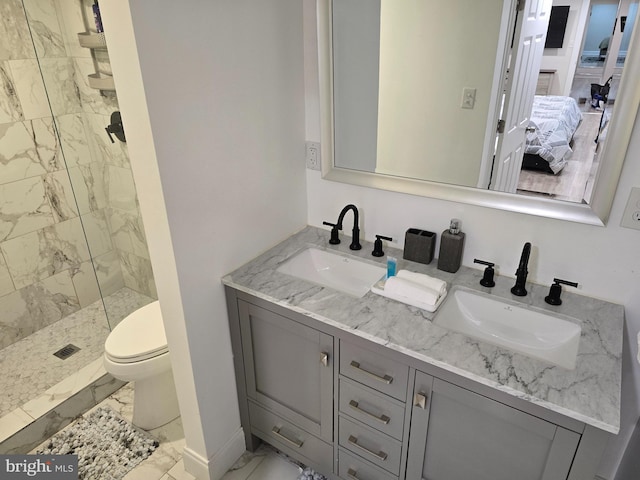 bathroom with vanity, toilet, and tiled shower