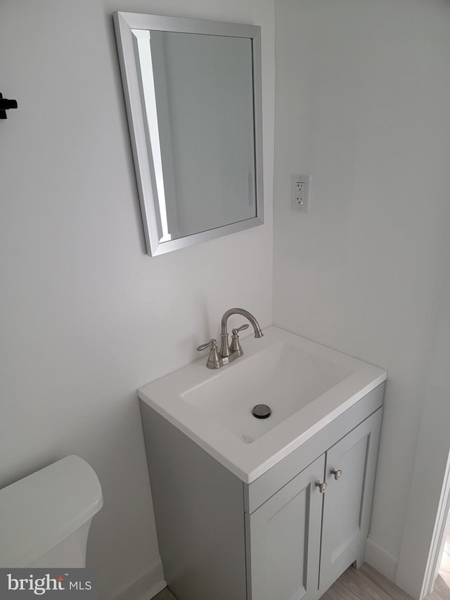 bathroom featuring vanity, hardwood / wood-style flooring, and toilet