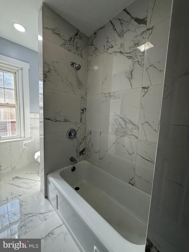 bathroom with tiled shower / bath combo and toilet