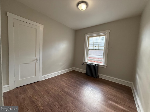 spare room with dark wood-type flooring and radiator