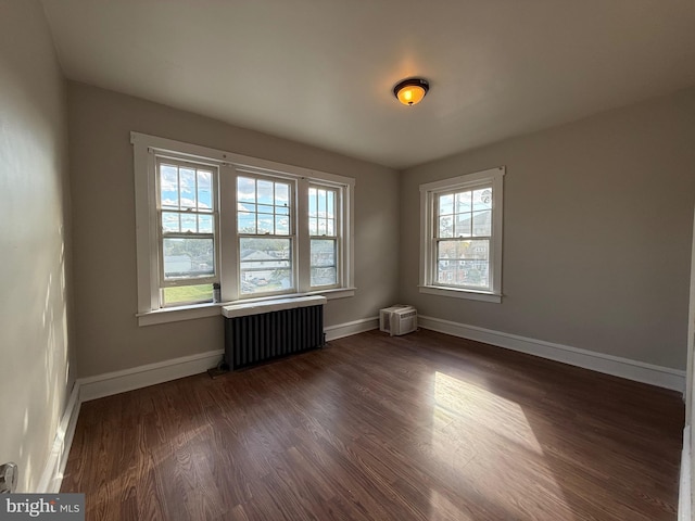 spare room featuring radiator heating unit and dark hardwood / wood-style floors