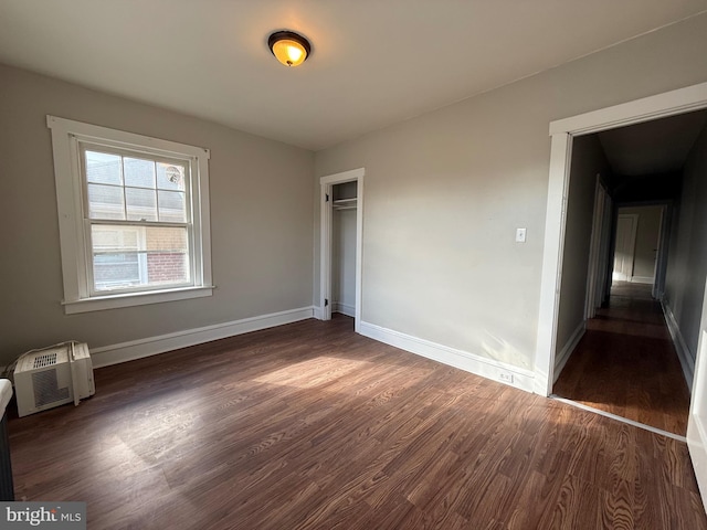 spare room with a wall mounted AC and dark wood-type flooring