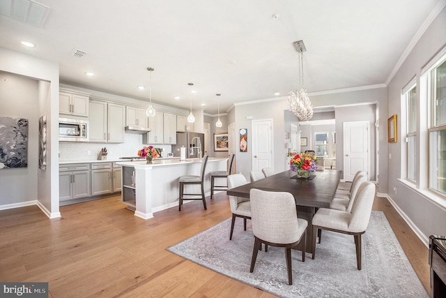 dining space featuring crown molding, light hardwood / wood-style flooring, and an inviting chandelier