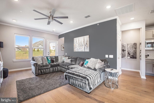 living room with crown molding, light wood-type flooring, and ceiling fan