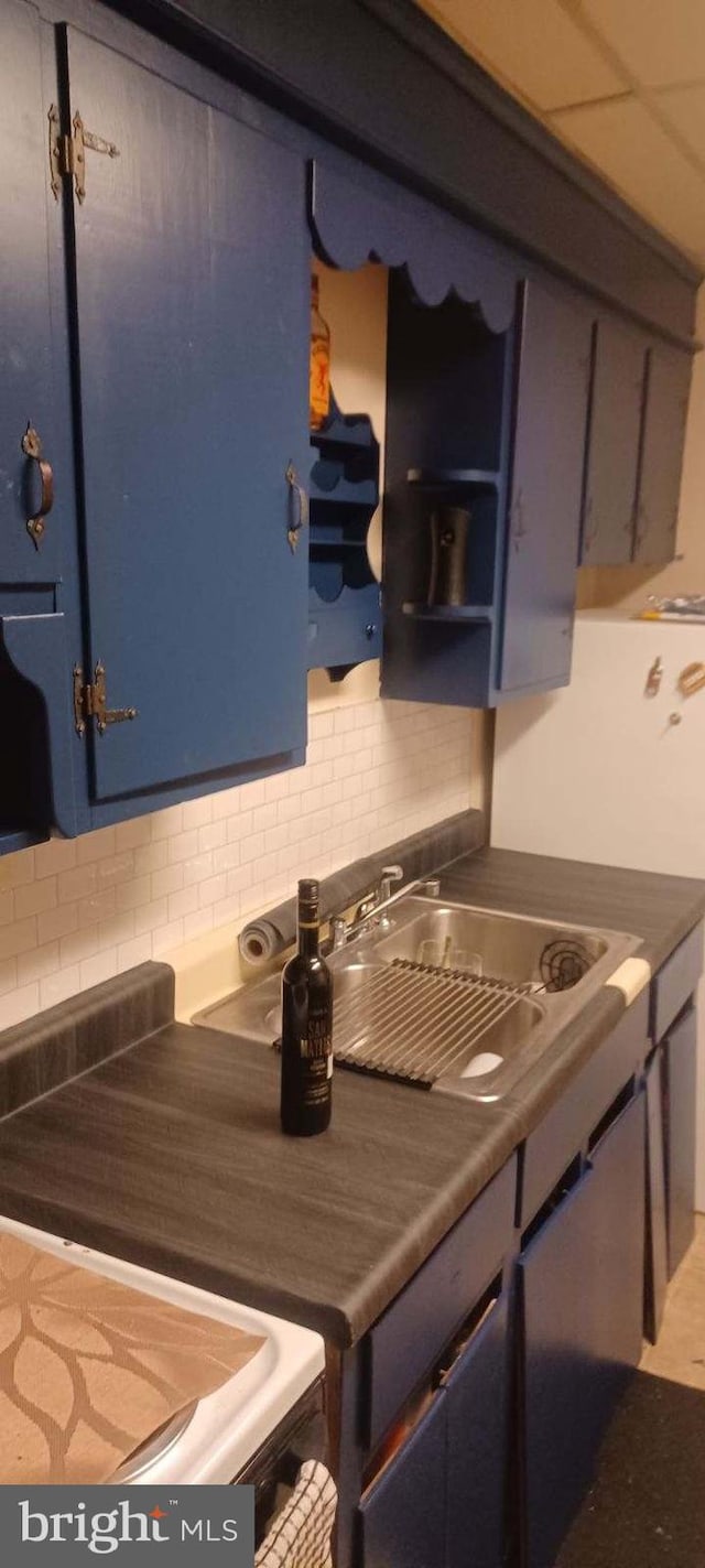 kitchen featuring blue cabinets, sink, tasteful backsplash, and range