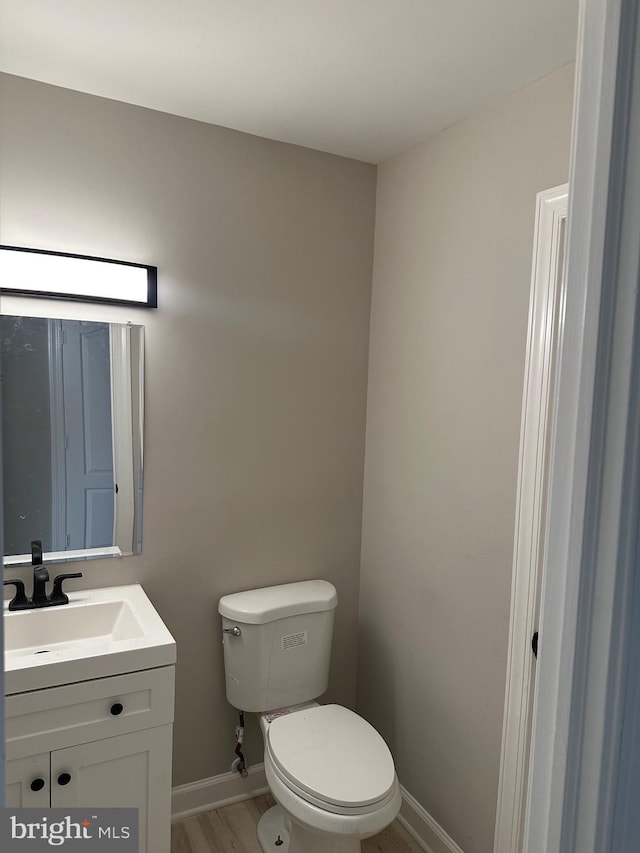 bathroom featuring toilet, vanity, and hardwood / wood-style flooring