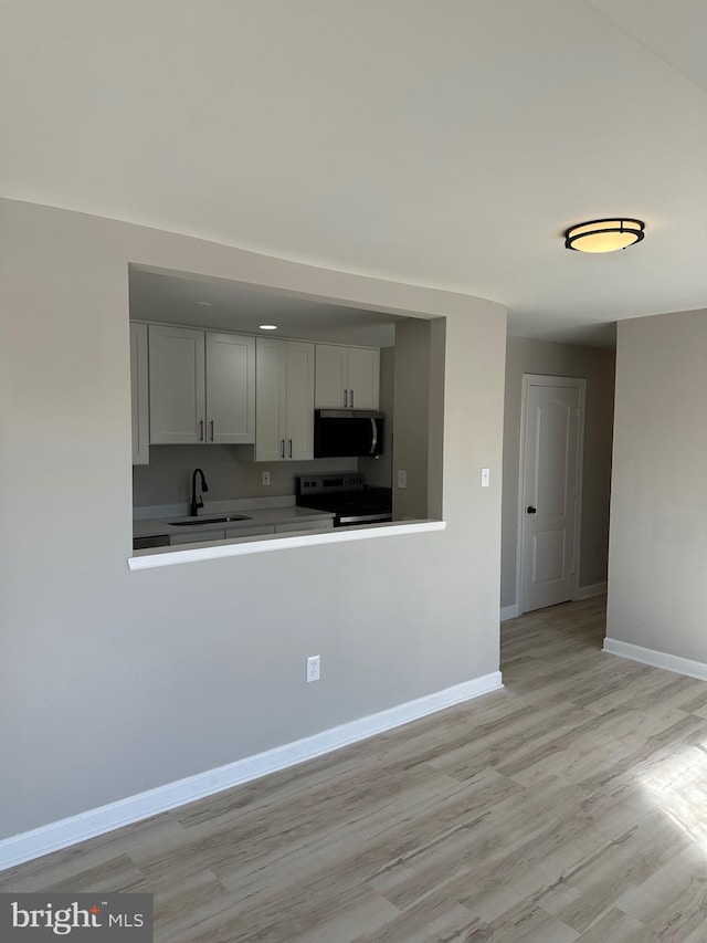 kitchen with white cabinets, sink, stainless steel appliances, and light hardwood / wood-style flooring