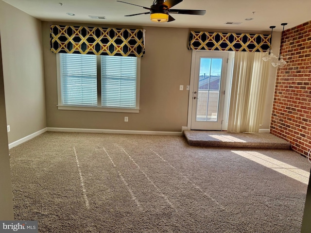 spare room with carpet, ceiling fan, and brick wall