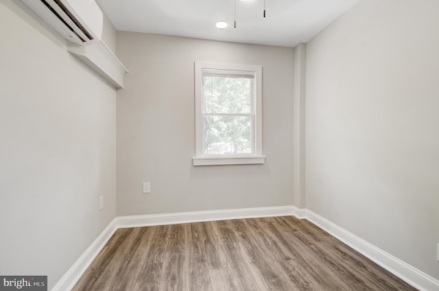 unfurnished room featuring an AC wall unit and hardwood / wood-style floors