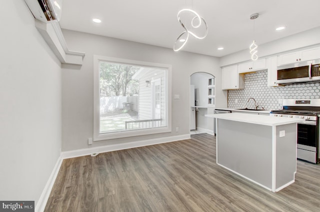 kitchen with white cabinets, light hardwood / wood-style flooring, sink, decorative light fixtures, and stainless steel appliances