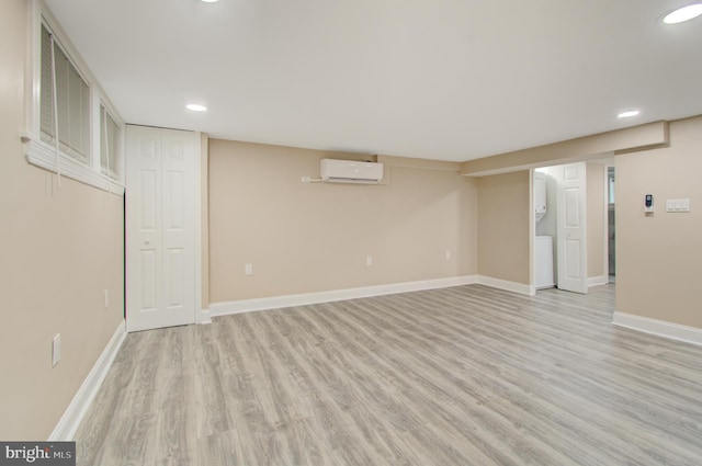 basement with a wall mounted air conditioner and light wood-type flooring