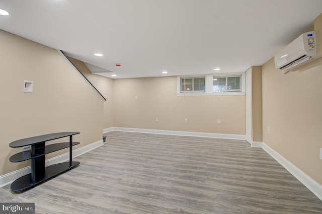 basement with light wood-type flooring and a wall mounted air conditioner