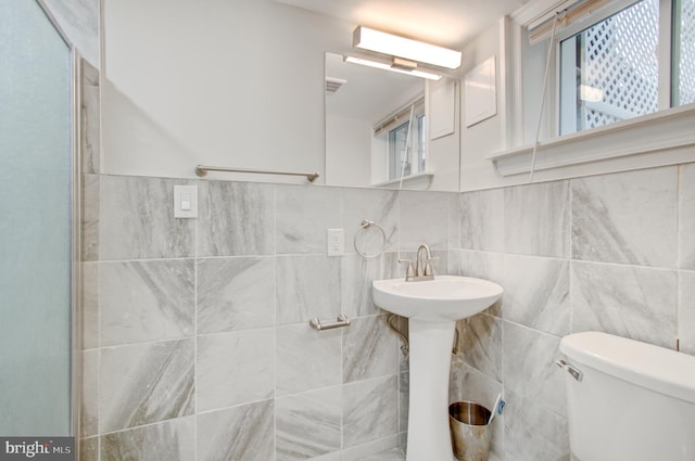 bathroom featuring toilet and tile walls