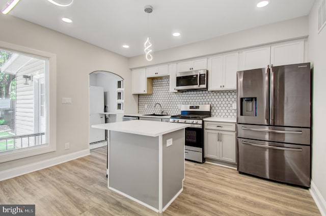 kitchen featuring light hardwood / wood-style floors, stainless steel appliances, pendant lighting, and white cabinets