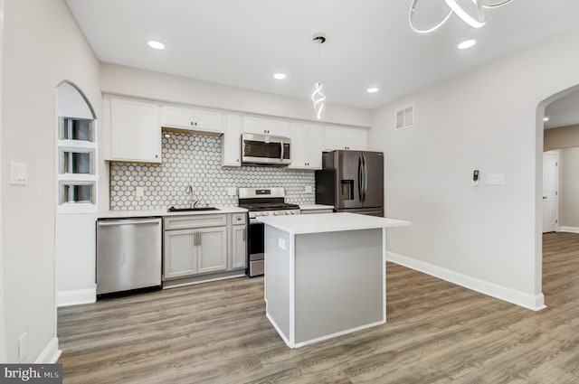 kitchen featuring appliances with stainless steel finishes, white cabinetry, decorative light fixtures, and sink