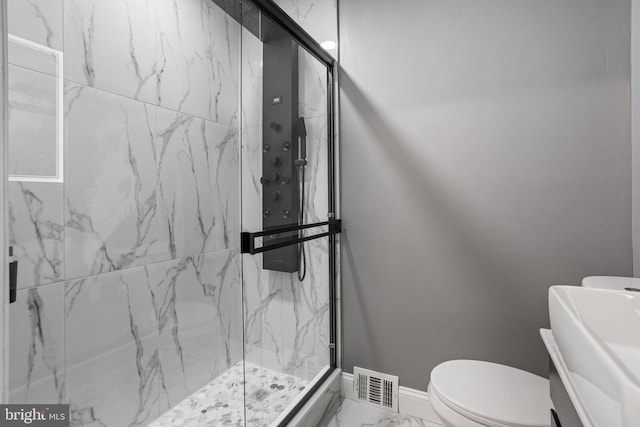 bathroom featuring a shower with door, toilet, and vanity