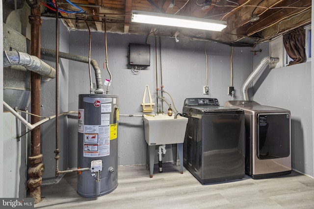 clothes washing area featuring gas water heater, wood-type flooring, and separate washer and dryer