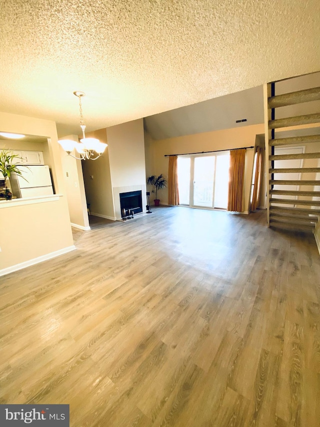 unfurnished living room featuring a textured ceiling, wood-type flooring, and an inviting chandelier