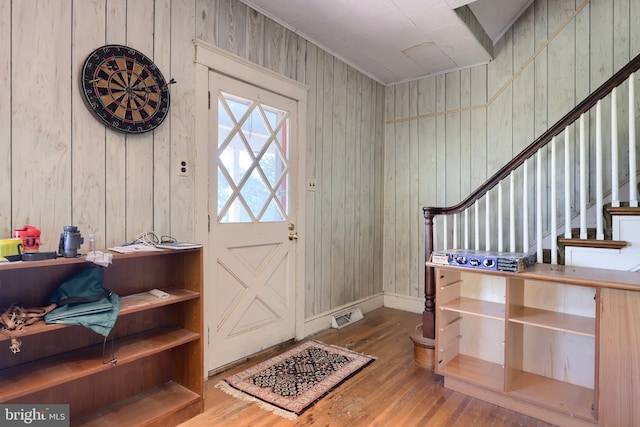 foyer entrance with hardwood / wood-style flooring and wooden walls