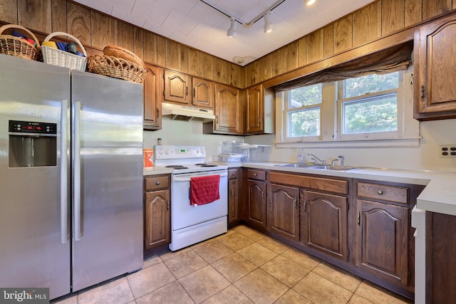 kitchen with electric range, light tile patterned floors, rail lighting, stainless steel refrigerator with ice dispenser, and sink