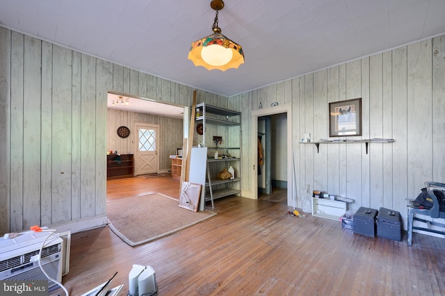 interior space with a wall unit AC, wood-type flooring, and wood walls