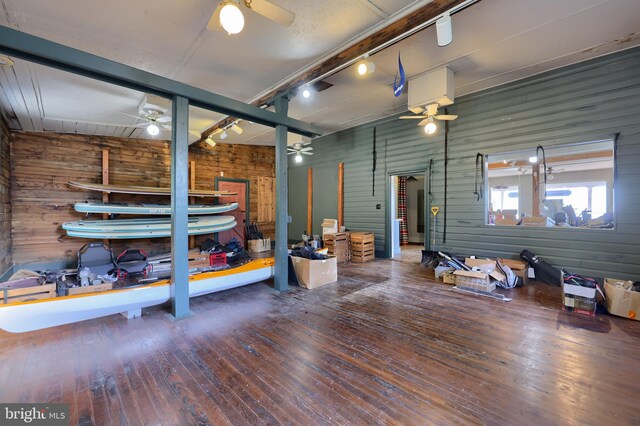 interior space featuring rail lighting, wooden walls, and hardwood / wood-style floors