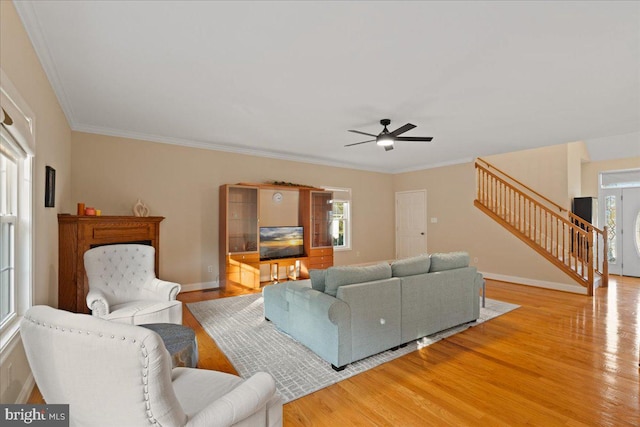 living room with light hardwood / wood-style flooring, a wealth of natural light, ornamental molding, and ceiling fan