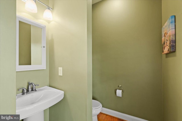 bathroom with toilet, sink, and hardwood / wood-style flooring